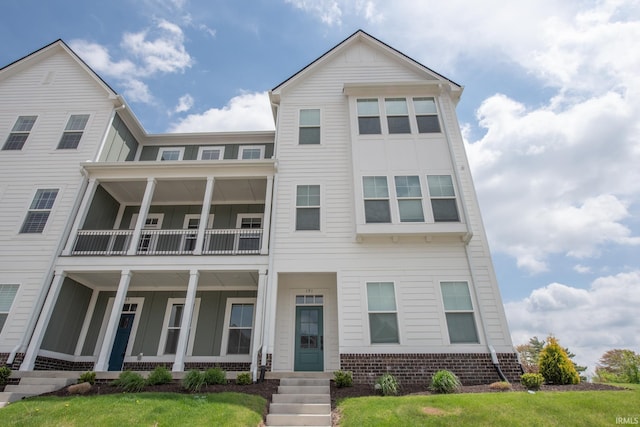 townhome / multi-family property with board and batten siding, brick siding, and a balcony