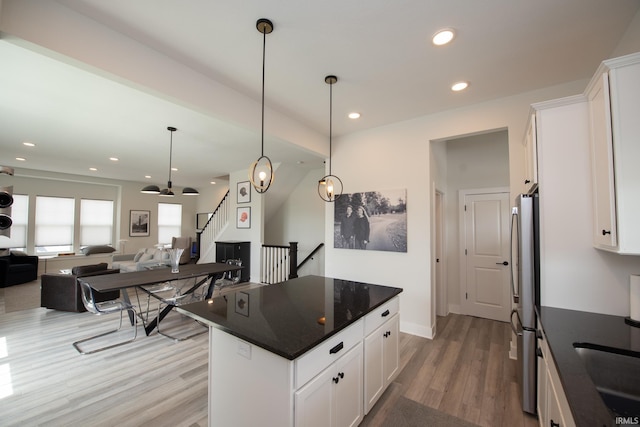 kitchen with white cabinets, hanging light fixtures, light wood-style flooring, freestanding refrigerator, and open floor plan