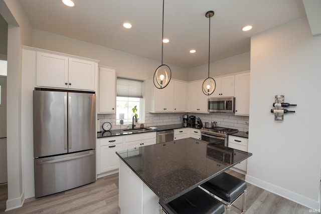 kitchen featuring light wood-style floors, white cabinets, stainless steel appliances, and tasteful backsplash