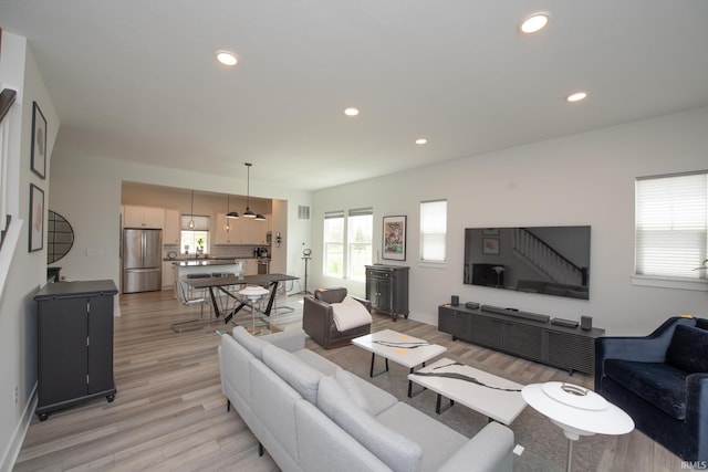 living room featuring recessed lighting, baseboards, and light wood-type flooring