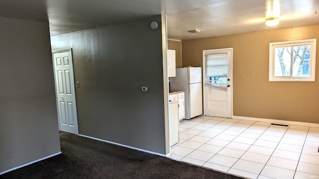 kitchen featuring visible vents, white cabinetry, baseboards, freestanding refrigerator, and light tile patterned flooring