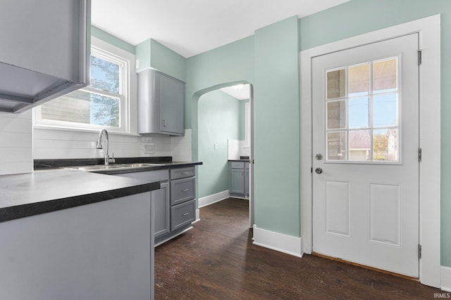 2922 Plaza Dr, Fort Wayne, IN 46806 - kitchen with decorative backsplash, dark wood-style flooring, gray cabinets, arched walkways, and a sink