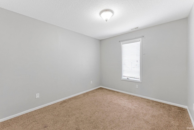 spare room featuring carpet floors, baseboards, a textured ceiling, and visible vents