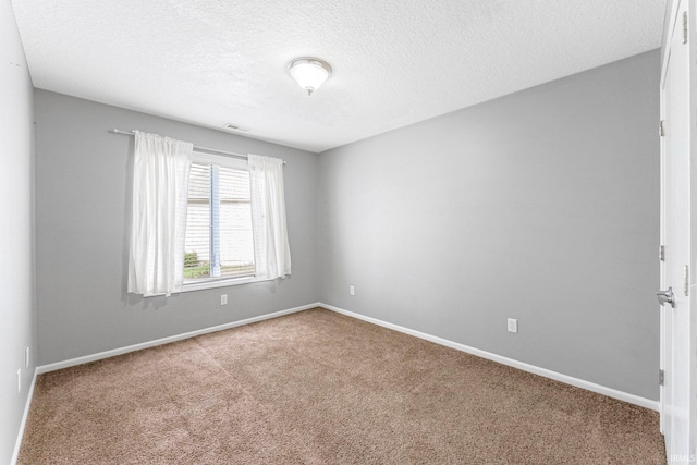 spare room featuring a textured ceiling, baseboards, and carpet