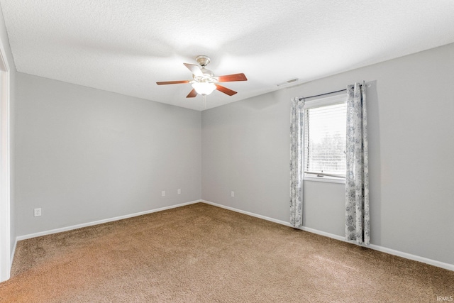 carpeted spare room featuring baseboards, a ceiling fan, and visible vents