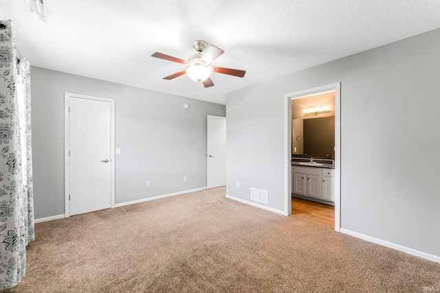 unfurnished bedroom featuring light colored carpet, baseboards, visible vents, and ensuite bath