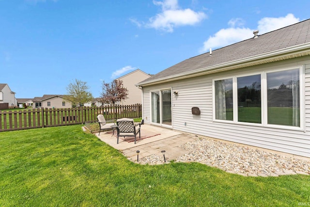 rear view of property featuring a patio, a lawn, and fence