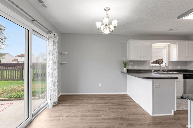 kitchen featuring dark countertops, white cabinets, light wood-type flooring, and visible vents