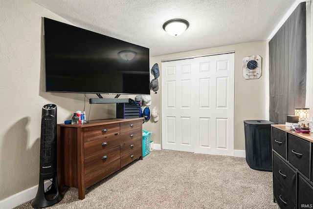bedroom with light colored carpet, a textured ceiling, baseboards, and a closet