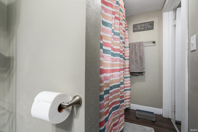 full bath featuring baseboards, curtained shower, and wood finished floors