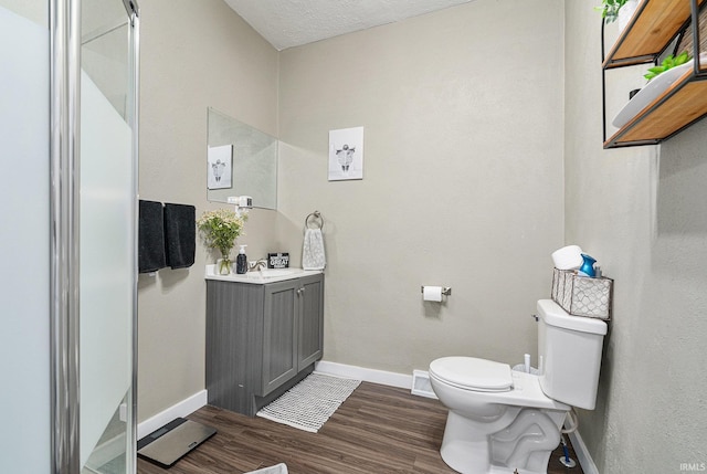 bathroom featuring toilet, baseboards, wood finished floors, and vanity
