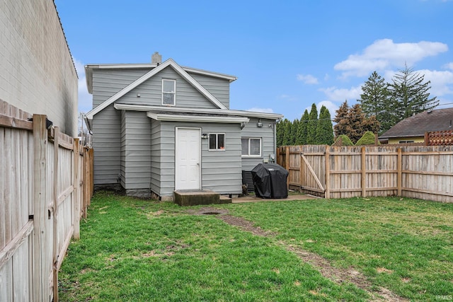 rear view of property featuring a fenced backyard and a lawn