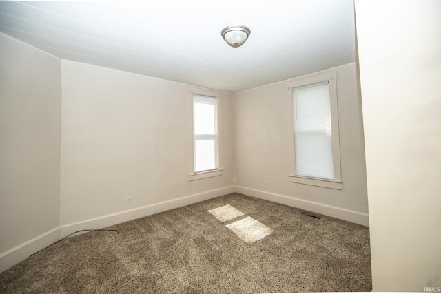 spare room with carpet flooring, baseboards, and visible vents