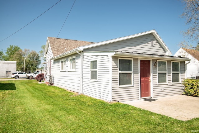 view of front of home featuring a shingled roof, a patio area, and a front yard
