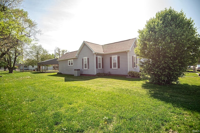 view of home's exterior featuring a lawn, a shingled roof, and central AC