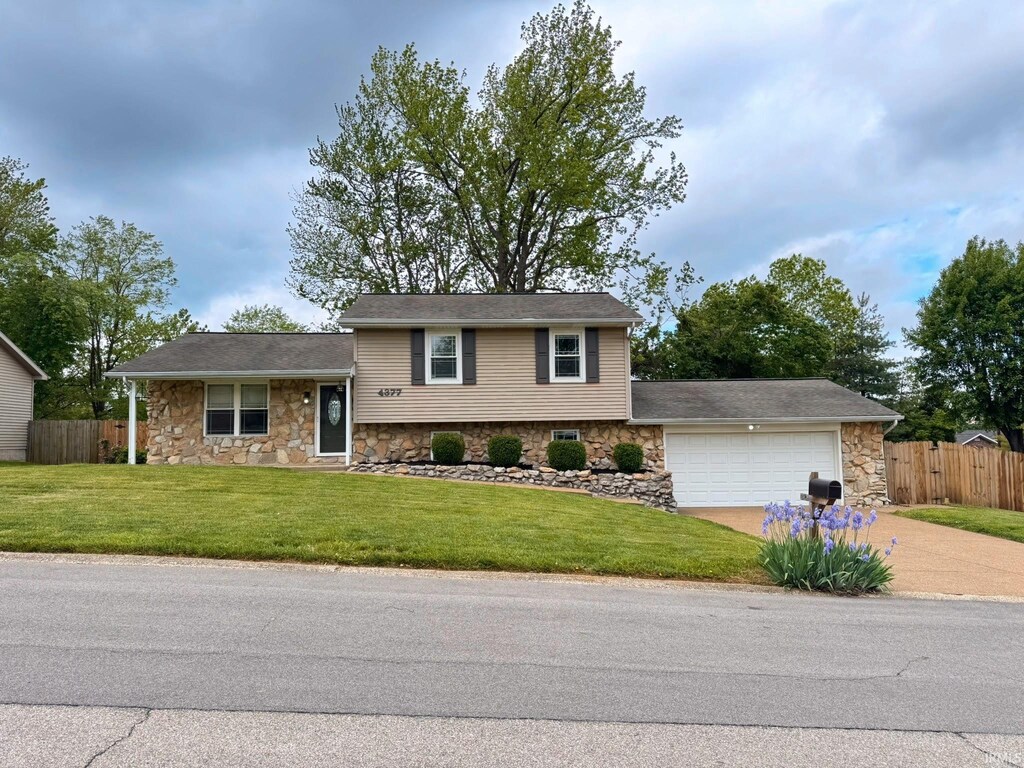 4377 Maryjoetta Dr, Newburgh, IN 47630 - tri-level home with driveway, fence, a front lawn, an attached garage, and stone siding