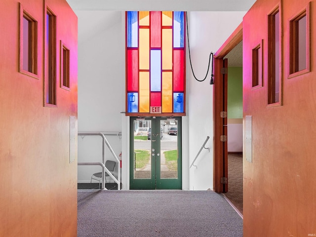 corridor featuring french doors, carpet, and a high ceiling