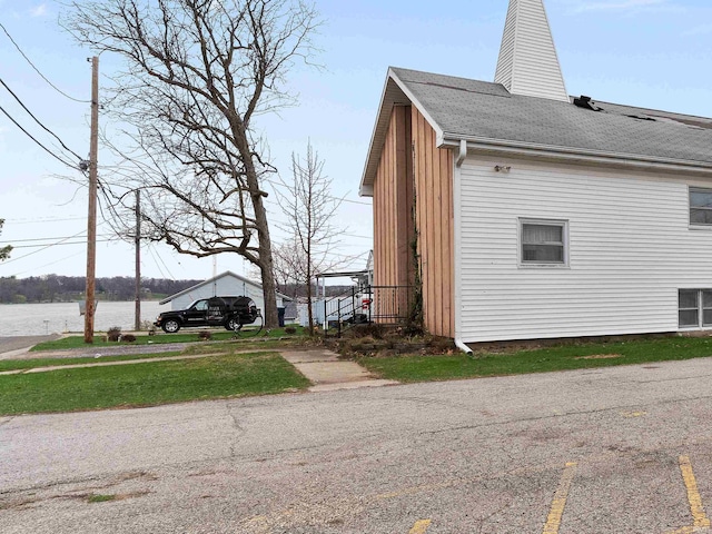 view of side of property with a water view, a chimney, and a shingled roof