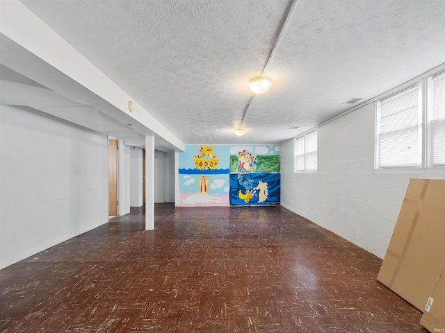 basement with visible vents, a textured ceiling, tile patterned floors, and concrete block wall