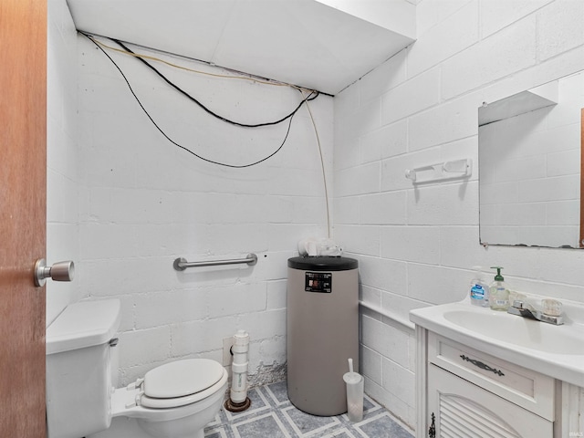 half bathroom featuring vanity, concrete block wall, tile patterned floors, and toilet