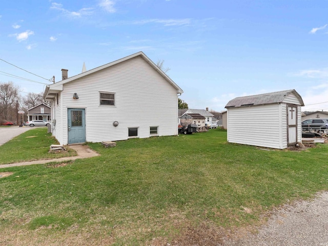 view of side of property featuring a lawn, an outbuilding, and a shed