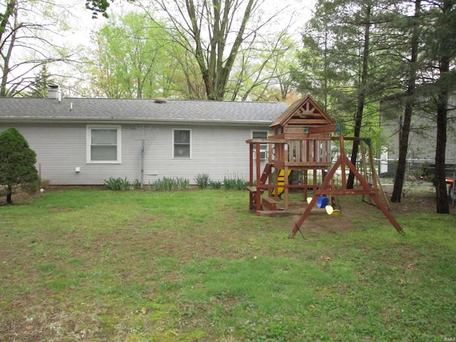 back of property with a yard, fence, a chimney, and a playground