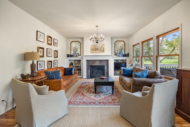 living room with a tiled fireplace, baseboards, and a notable chandelier
