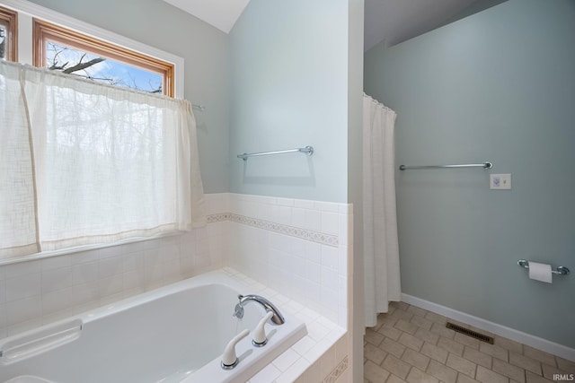 bathroom with visible vents, baseboards, tile patterned floors, a bath, and vaulted ceiling