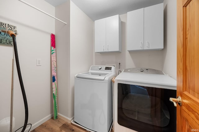 laundry area with baseboards, light wood-type flooring, cabinet space, and washer and clothes dryer