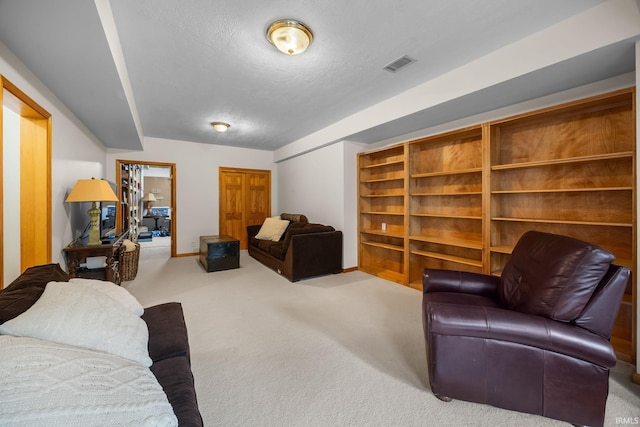 living area featuring visible vents, a textured ceiling, carpet, and baseboards