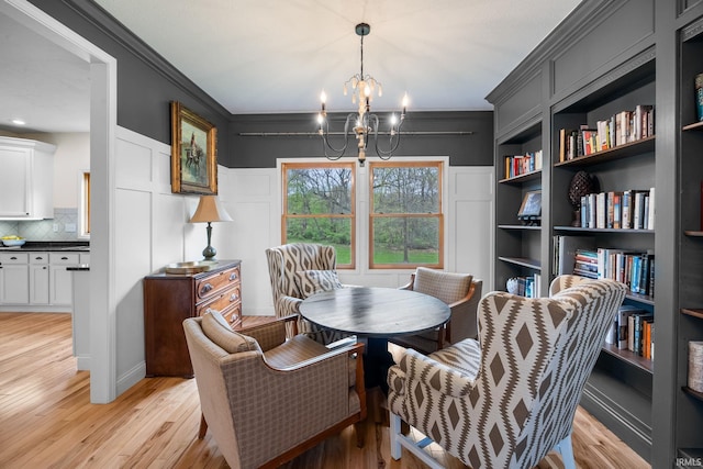 dining area with an inviting chandelier, ornamental molding, and light wood-type flooring