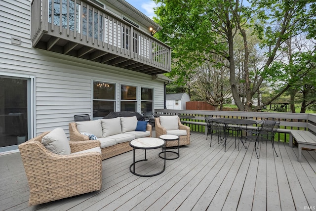 wooden terrace with an outdoor structure, outdoor dining area, a shed, and an outdoor hangout area