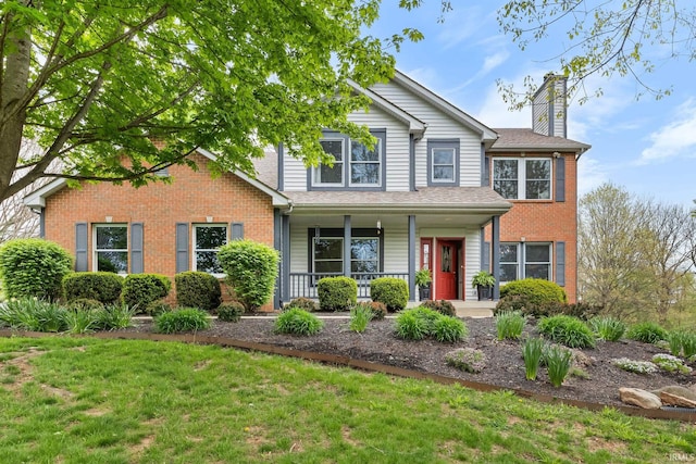 traditional-style house featuring a chimney, a porch, a front lawn, and brick siding