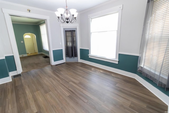 unfurnished dining area featuring baseboards, a chandelier, ornamental molding, and a wealth of natural light