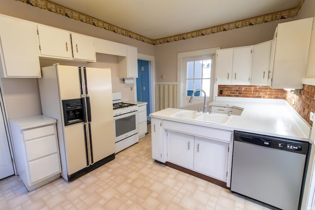 kitchen with wainscoting, a sink, white appliances, light countertops, and white cabinetry