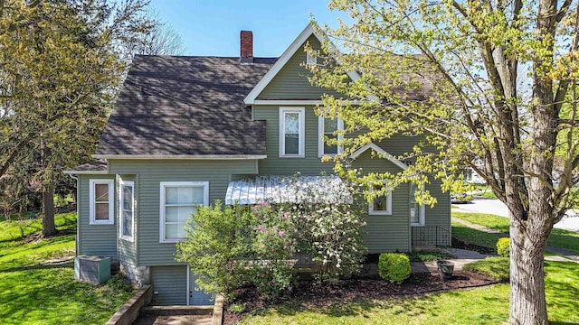 view of front of home with central AC unit, a front lawn, roof with shingles, and a chimney