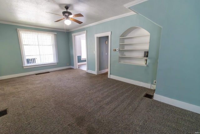 spare room with ornamental molding, a ceiling fan, dark carpet, and visible vents