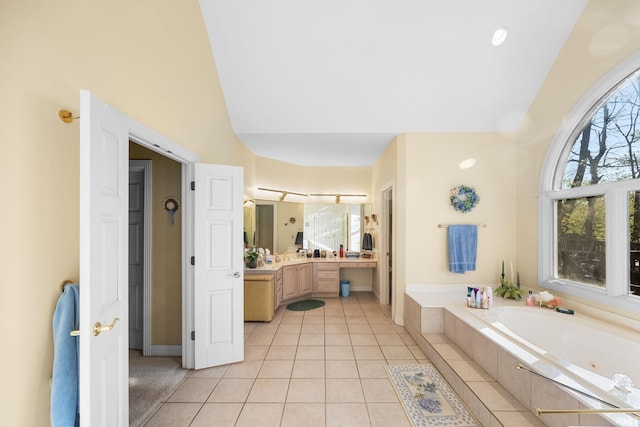 full bathroom with a jetted tub, tile patterned flooring, vaulted ceiling, vanity, and baseboards