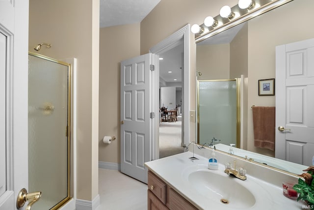 bathroom featuring baseboards, a shower stall, and vanity