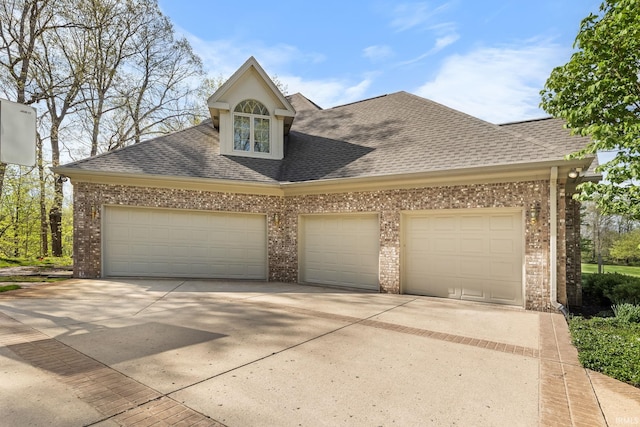 view of front of house featuring roof with shingles, concrete driveway, and brick siding
