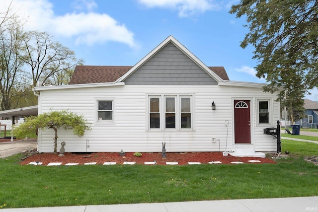 view of front facade featuring a shingled roof, driveway, a front yard, and a carport