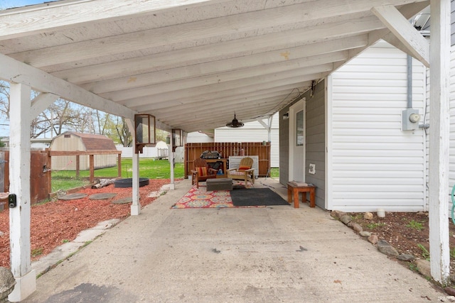 view of patio / terrace with an outdoor structure, a shed, an attached carport, and fence