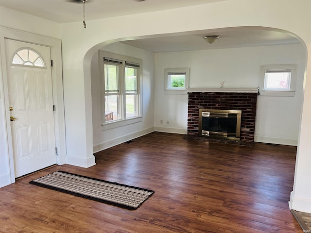 entryway featuring plenty of natural light, arched walkways, wood finished floors, and a fireplace