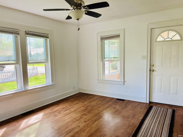 entrance foyer featuring visible vents, a ceiling fan, baseboards, and wood finished floors