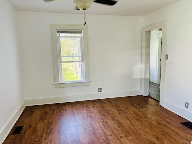 empty room featuring baseboards, ceiling fan, visible vents, and wood finished floors