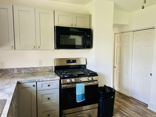 kitchen featuring black microwave, light countertops, dark wood-type flooring, and gas range
