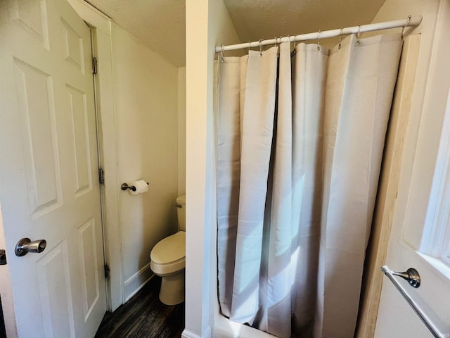 full bath featuring baseboards, toilet, a shower with curtain, and wood finished floors