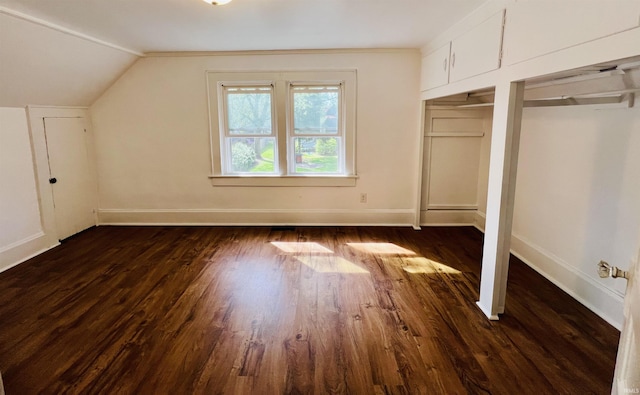 unfurnished bedroom with dark wood-type flooring, baseboards, and lofted ceiling