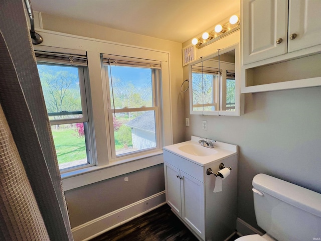bathroom featuring vanity, baseboards, wood finished floors, and toilet