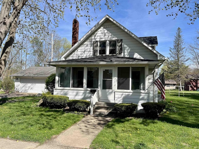 bungalow-style house featuring a garage, a chimney, a sunroom, and a front lawn
